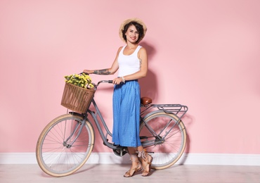 Photo of Portrait of beautiful young woman with bicycle near color wall