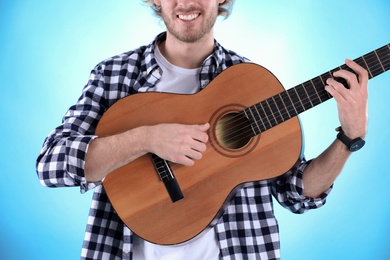 Photo of Young man playing acoustic guitar on color background, closeup