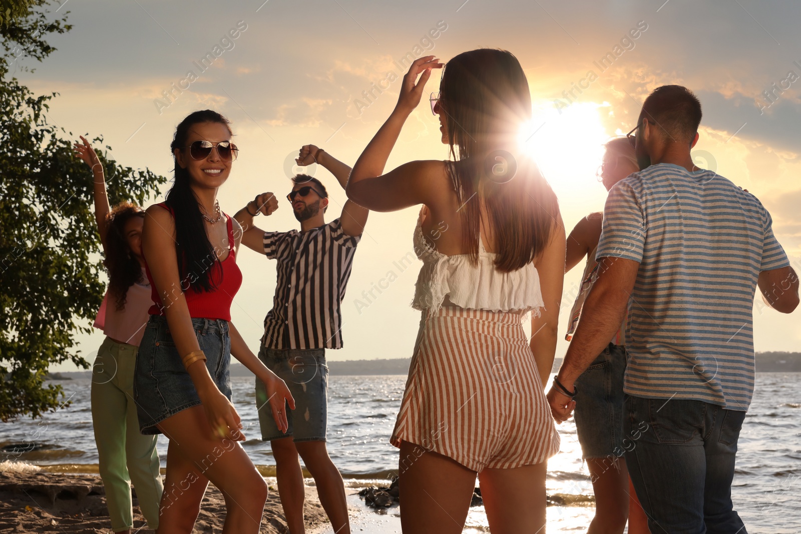 Photo of Group of friends having fun near river at summer party