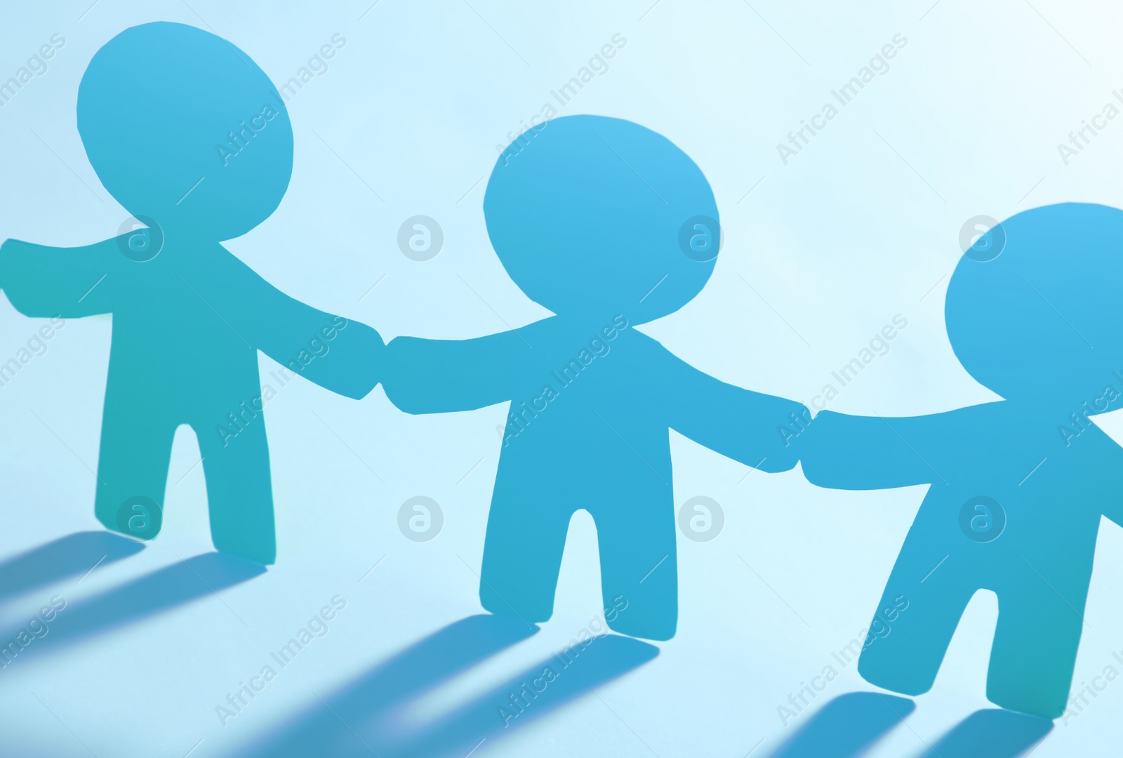 Photo of Paper people holding hands on light background. Unity concept