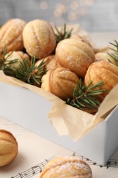 Homemade walnut shaped cookies and fir branches in box on note sheets, closeup