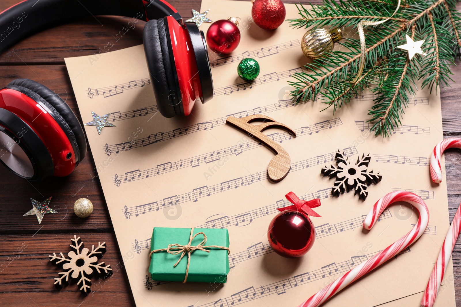 Photo of Christmas decorations, headphones and music sheets on wooden table
