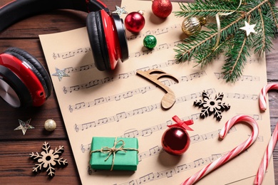 Christmas decorations, headphones and music sheets on wooden table