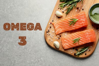 Image of Omega 3. Board with fresh cut salmon, rosemary and spices on grey table, top view