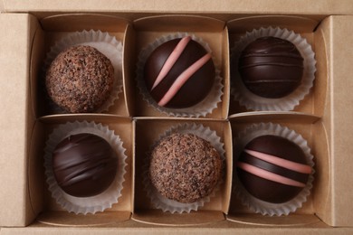 Photo of Many different delicious chocolate truffles in box, top view