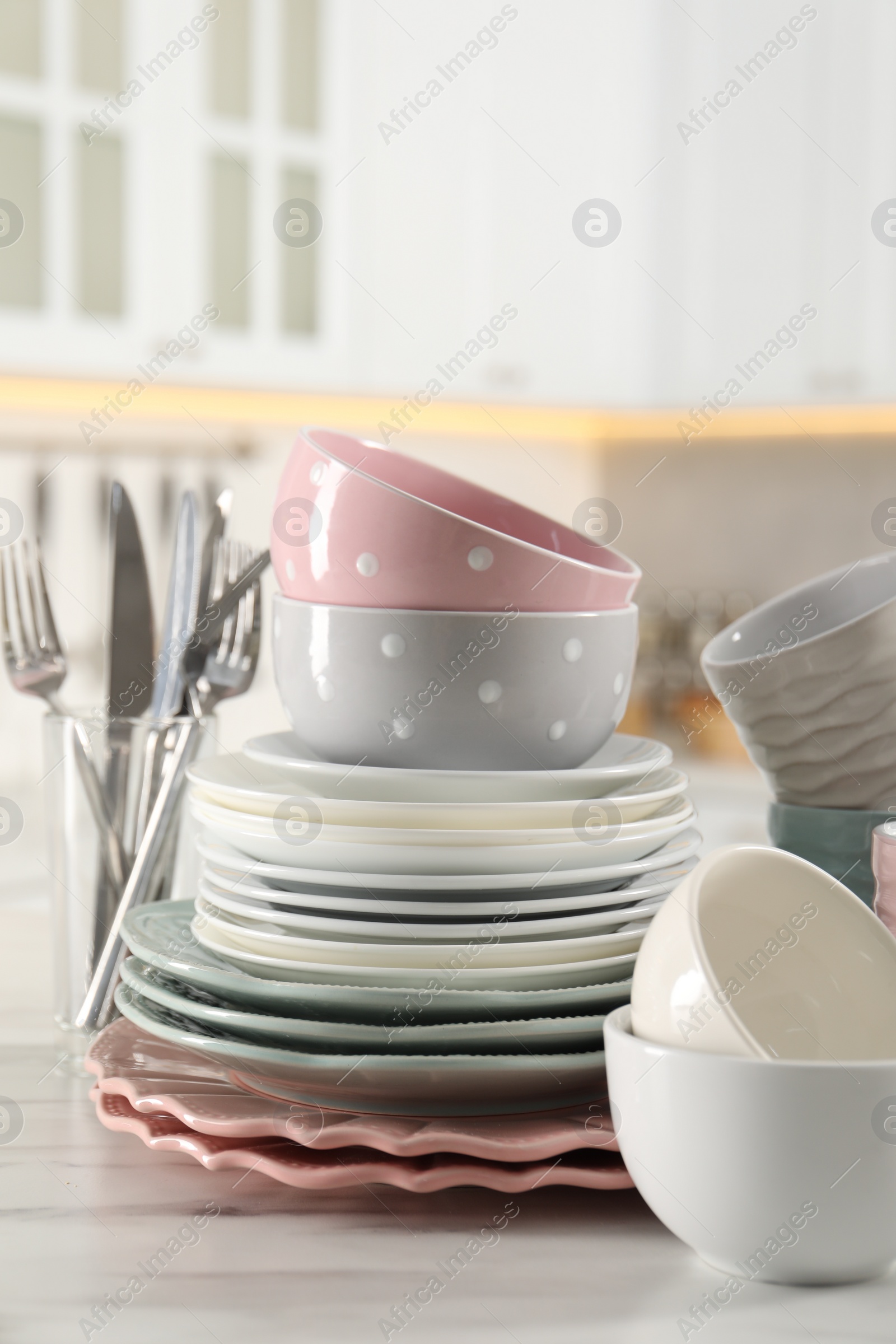 Photo of Many different clean dishware on white marble table in kitchen