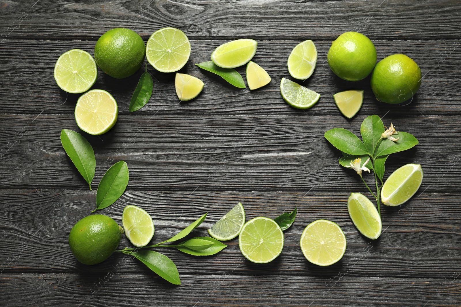 Photo of Frame of fresh ripe limes on wooden background, top view