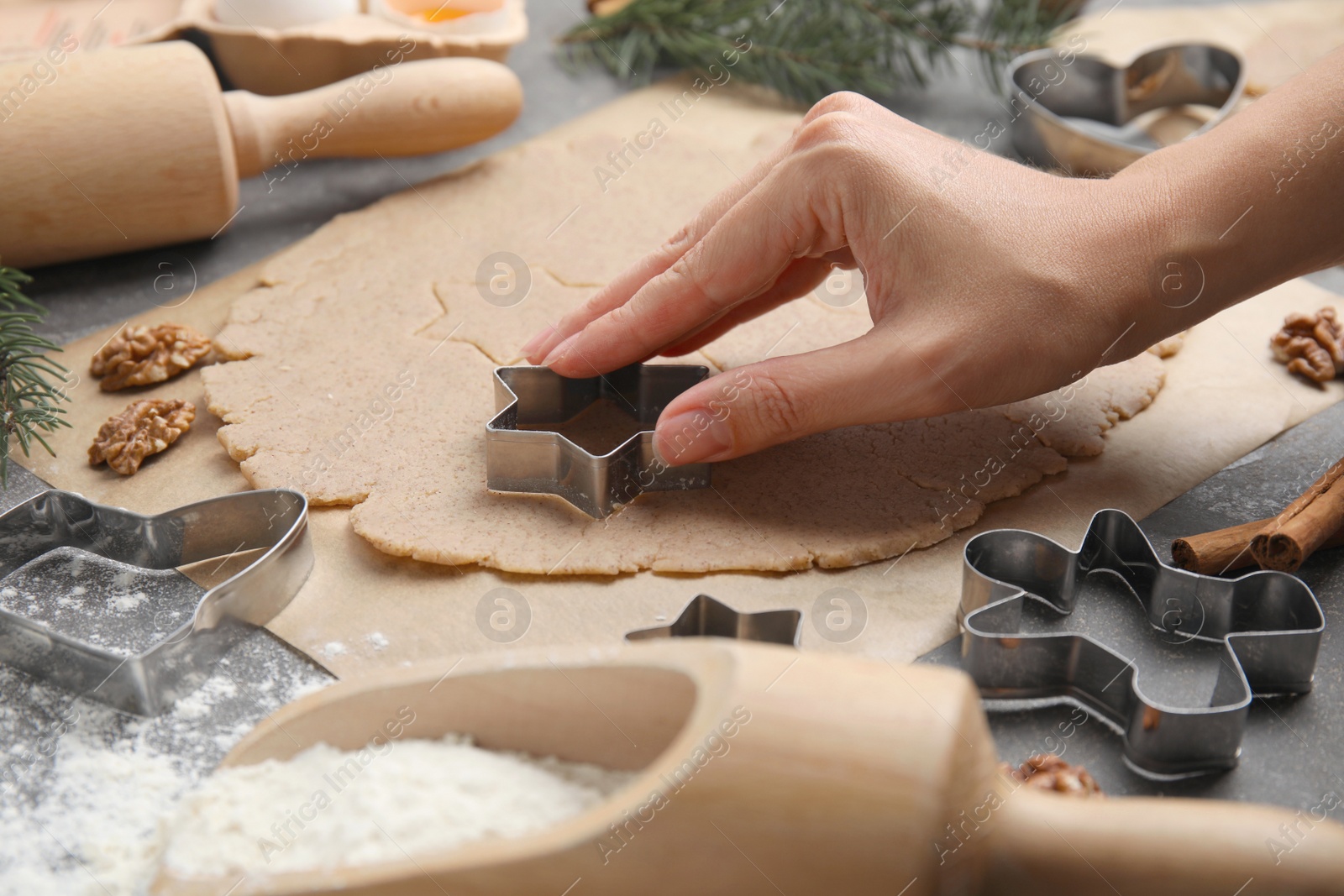 Photo of Woman making gingerbread star with cutter at table, closeup. Homemade Christmas biscuits