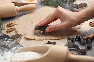 Woman making gingerbread star with cutter at table, closeup. Homemade Christmas biscuits