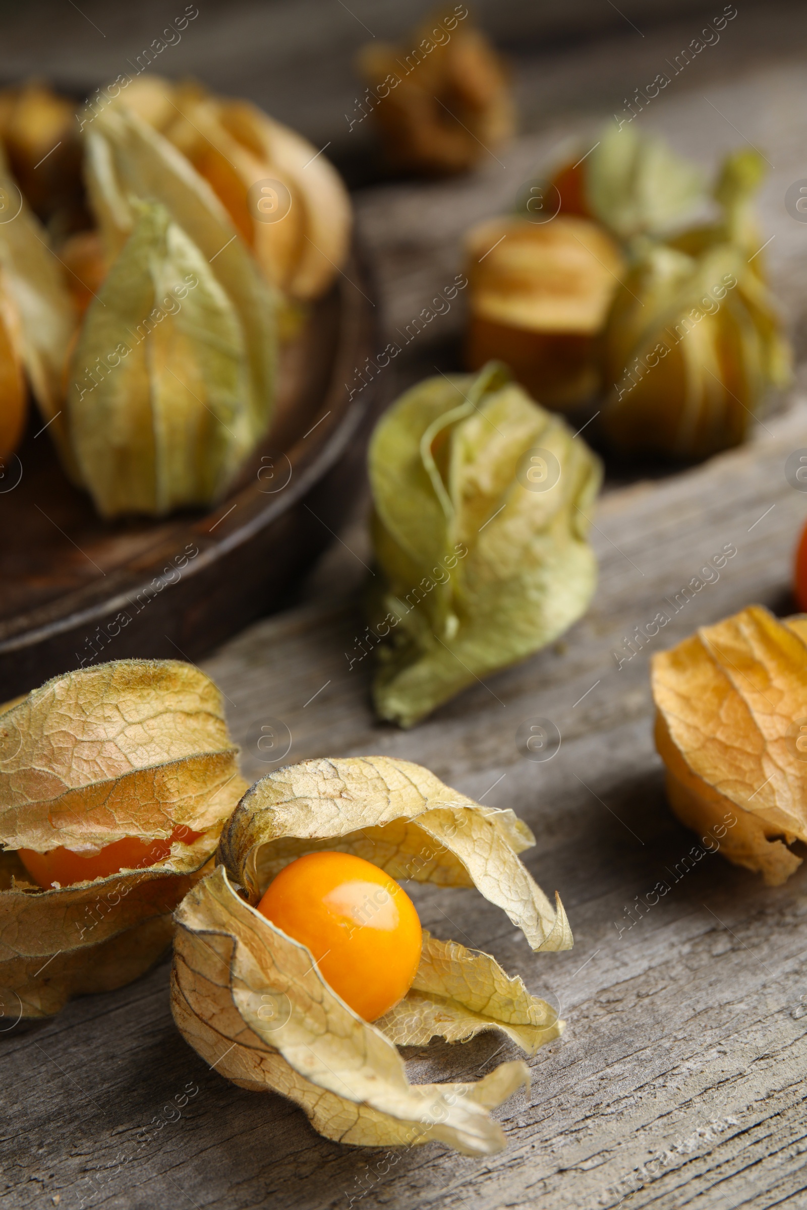 Photo of Ripe physalis fruits with dry husk on wooden table, closeup