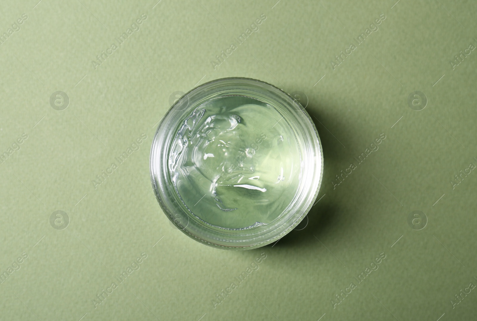 Photo of Aloe gel in jar on olive background, top view
