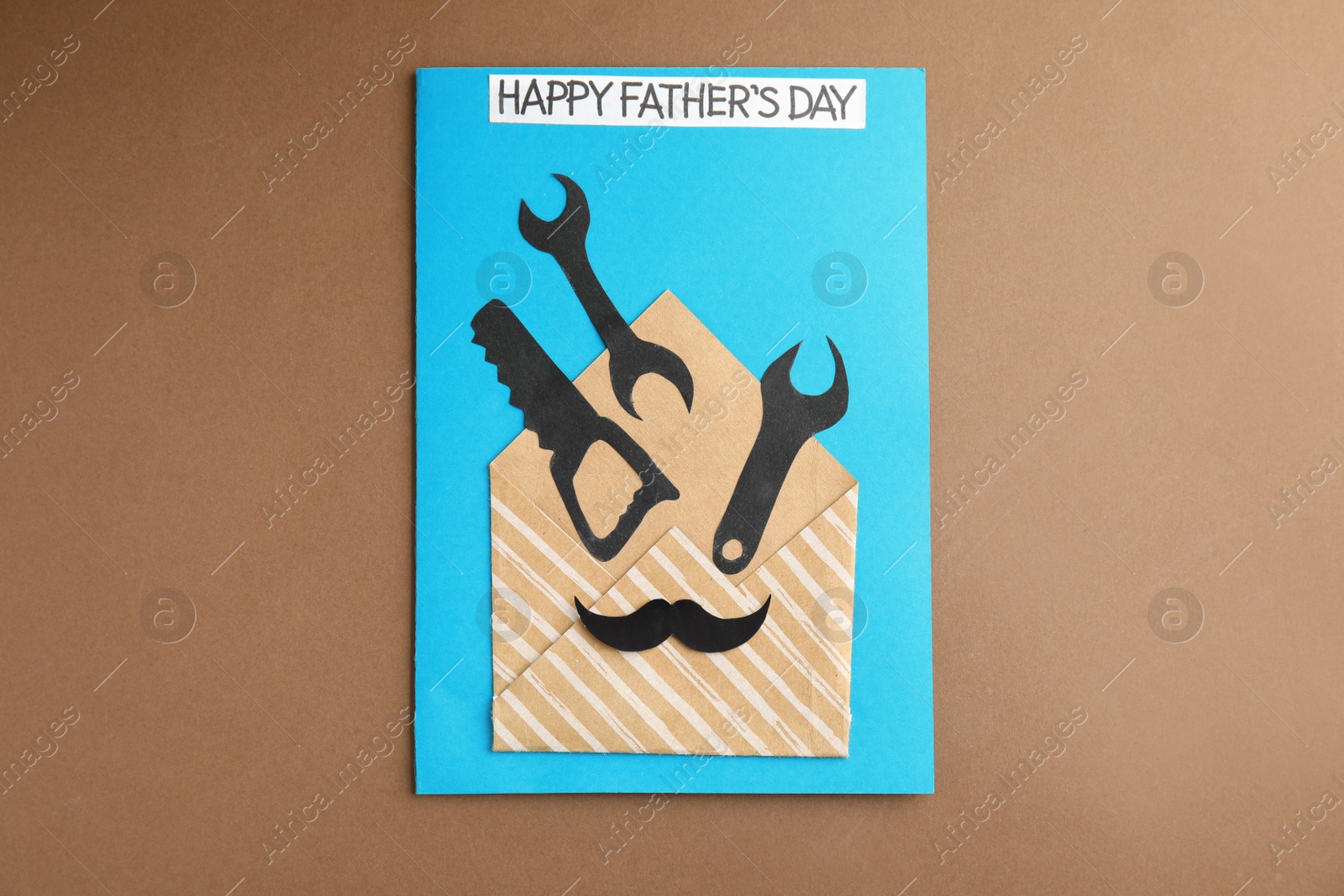 Photo of Greeting card with phrase HAPPY FATHER'S DAY on brown background, top view