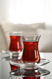 Glass of traditional Turkish tea on table indoors, space for text