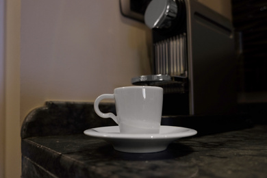 White cup near coffee machine on table