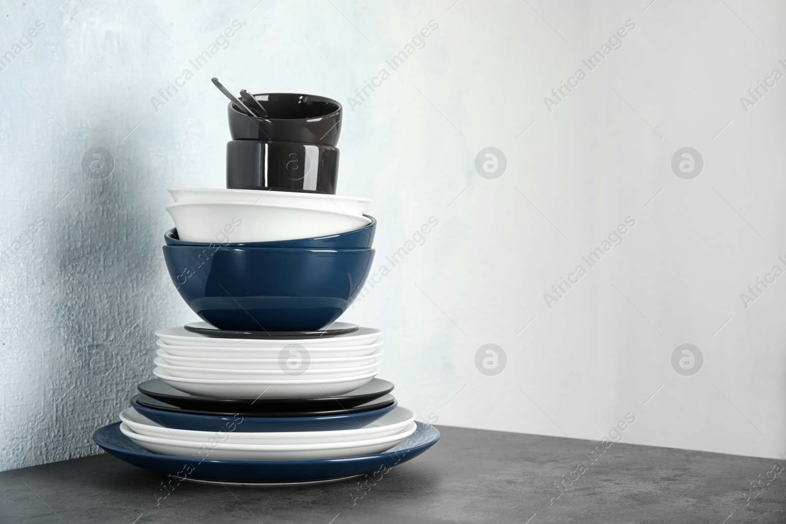 Photo of Set of dinnerware on table against light background with space for text. Interior element