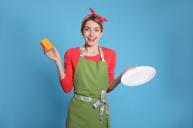Photo of Young housewife with plate and sponge on light blue background