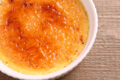 Photo of Delicious creme brulee in bowl on wooden table, top view