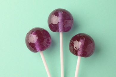 Tasty lollipops on turquoise background, flat lay