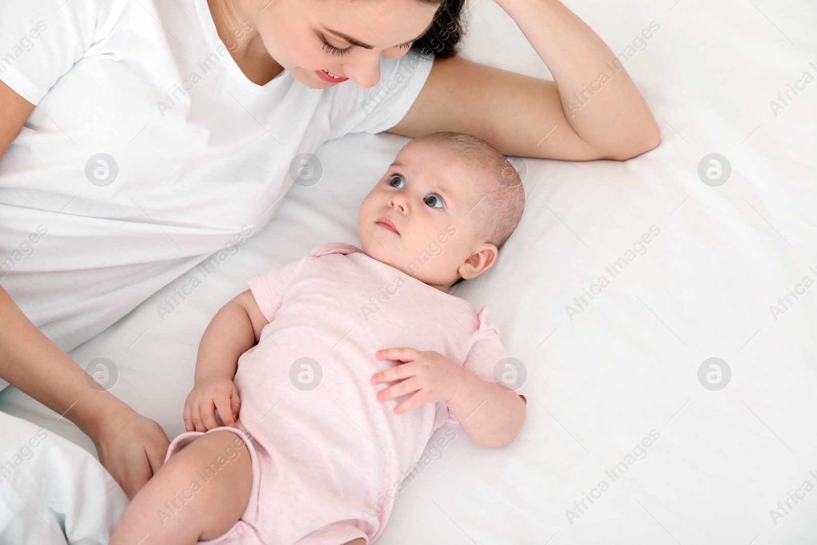 Photo of Cute baby with mother lying on bed, above view. Space for text
