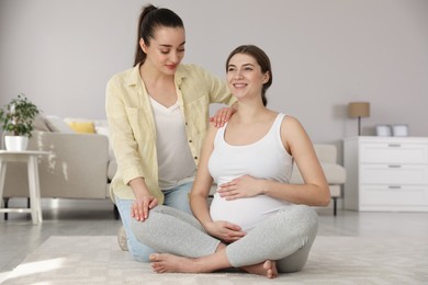 Photo of Doula working with pregnant woman in living room. Preparation for child birth