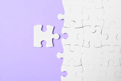 Blank white puzzle pieces on violet background, flat lay