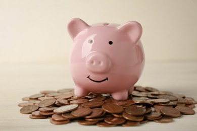 Photo of Ceramic piggy bank and coins on white wooden table, closeup