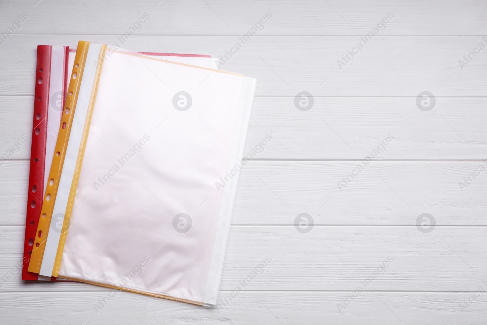 Photo of File folders with punched pockets on white wooden table, flat lay. Space for text