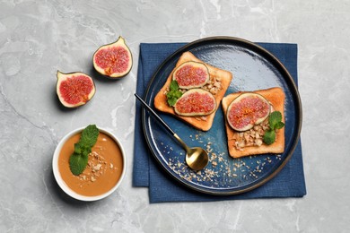 Photo of Tasty toasts served with fig, peanut butter and walnuts on light grey marble table, flat lay