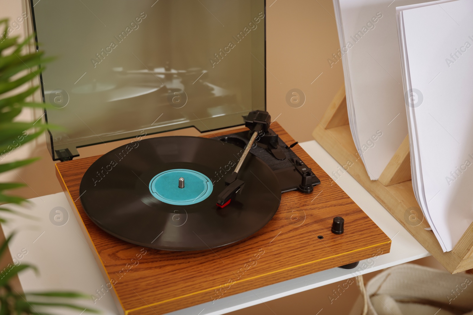 Photo of Stylish turntable with vinyl record on white table indoors