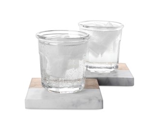 Glasses of cold drink and stylish stone cup coasters on white background