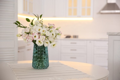 Bouquet of beautiful flowers on table in kitchen, space for text. Interior design