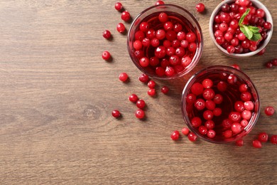 Tasty cranberry juice in glasses and fresh berries on wooden table, flat lay. Space for text