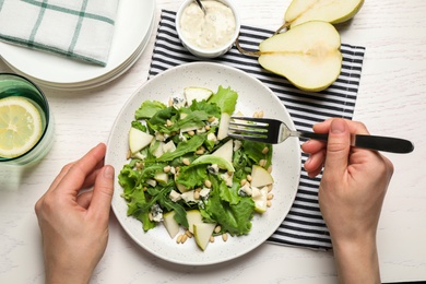 Photo of Woman with tasty pear salad at white table, top view