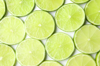 Photo of Fresh juicy lime slices on white background, flat lay