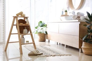 Photo of Dispensers and different toiletries on decorative ladder in bathroom. Idea for interior design