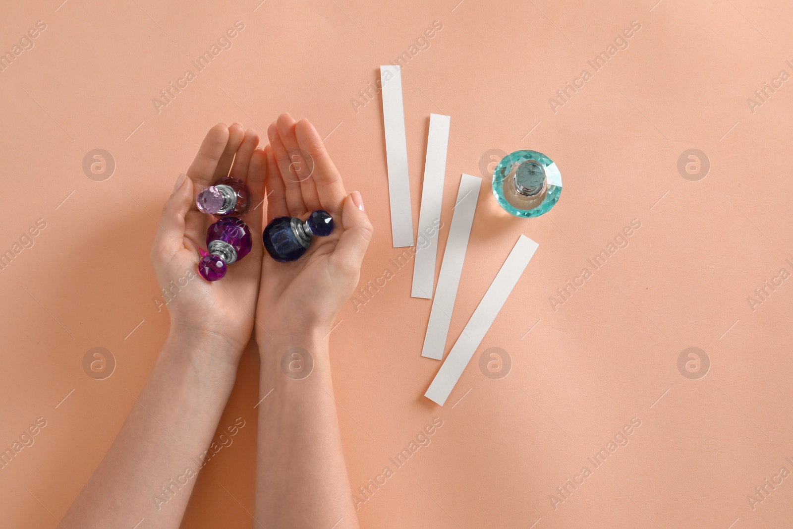 Photo of Woman with perfume bottles on peach background, top view