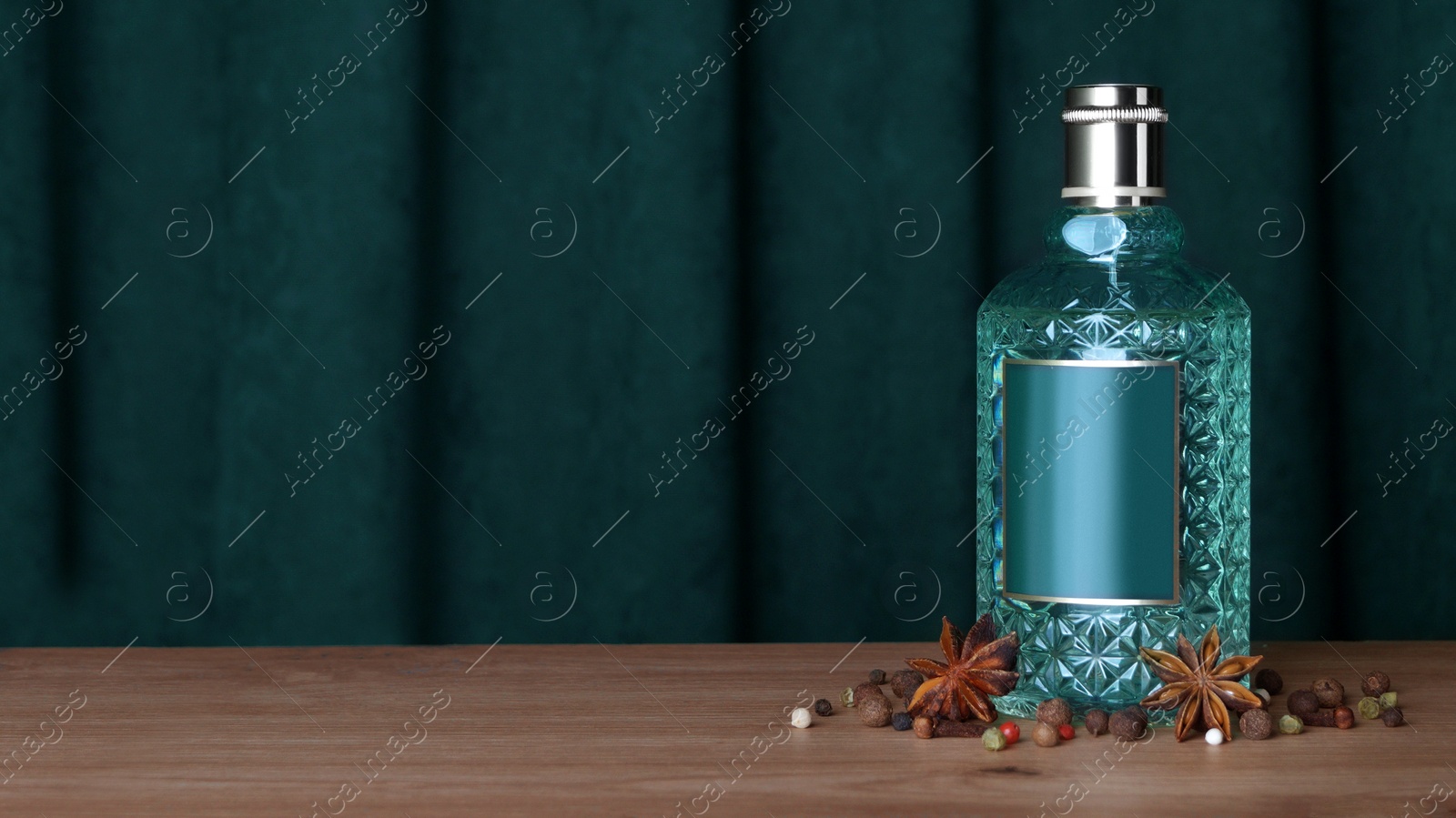 Photo of Bottle of perfume and different spices on wooden table. Space for text