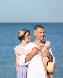 Happy mature couple at beach on sunny day