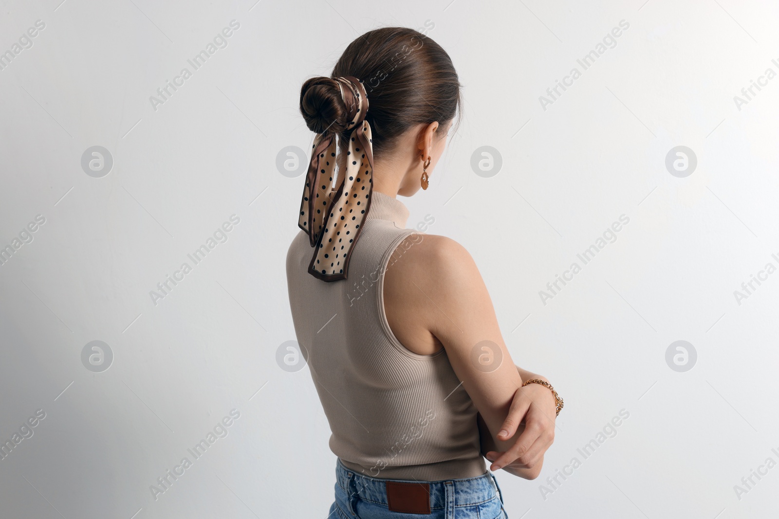 Photo of Young woman with stylish bandana on light background, back view