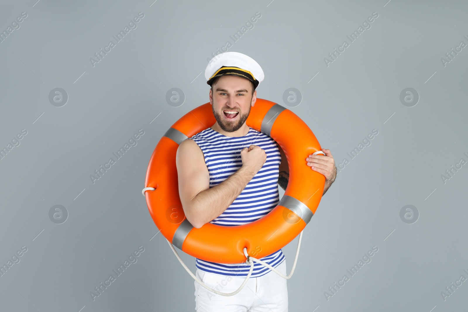 Photo of Happy sailor with ring buoy on light grey background