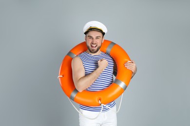 Photo of Happy sailor with ring buoy on light grey background