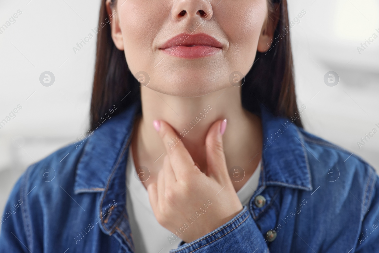 Photo of Endocrine system. Woman doing thyroid self examination indoors, closeup