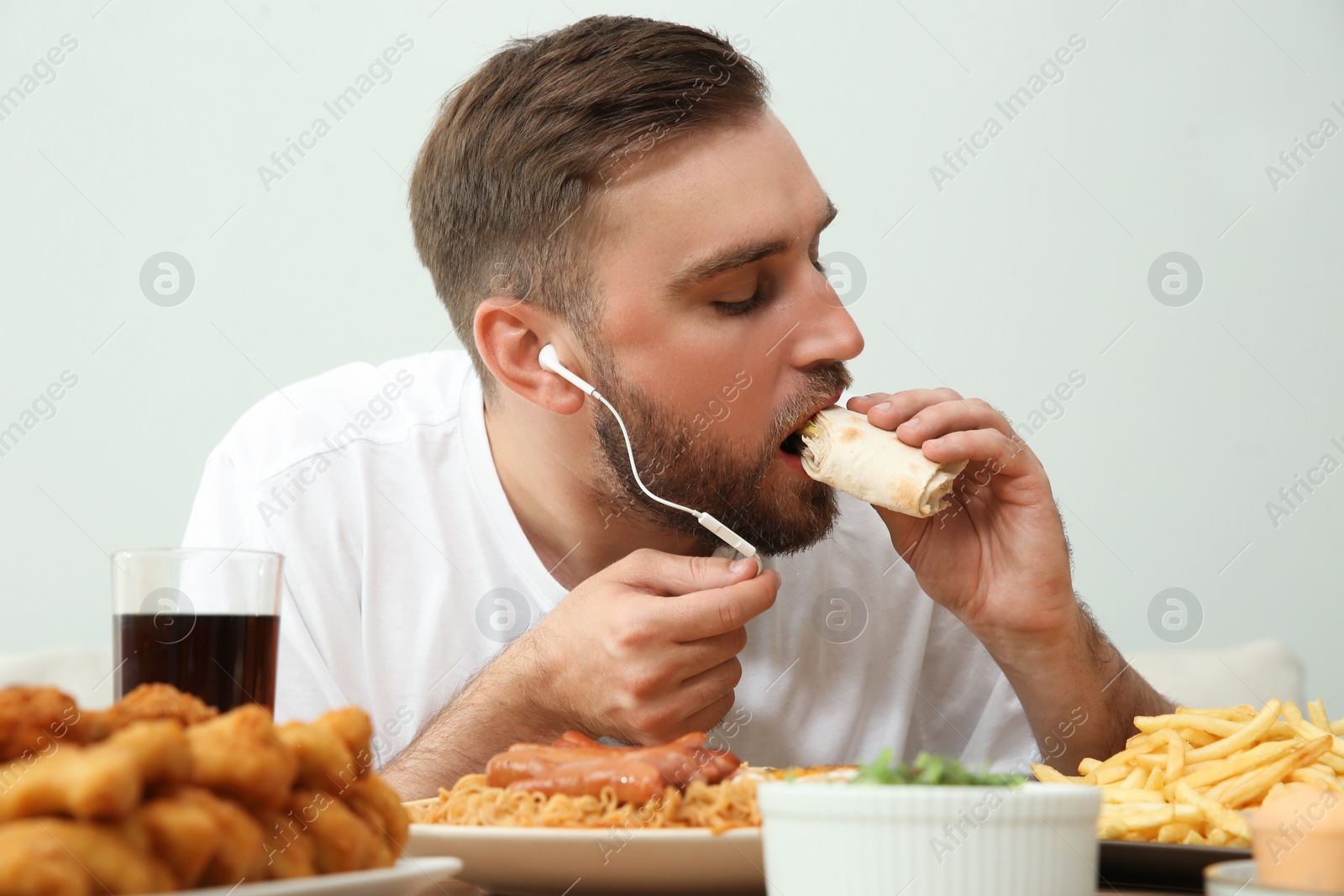 Photo of Food blogger eating at table against light background. Mukbang vlog