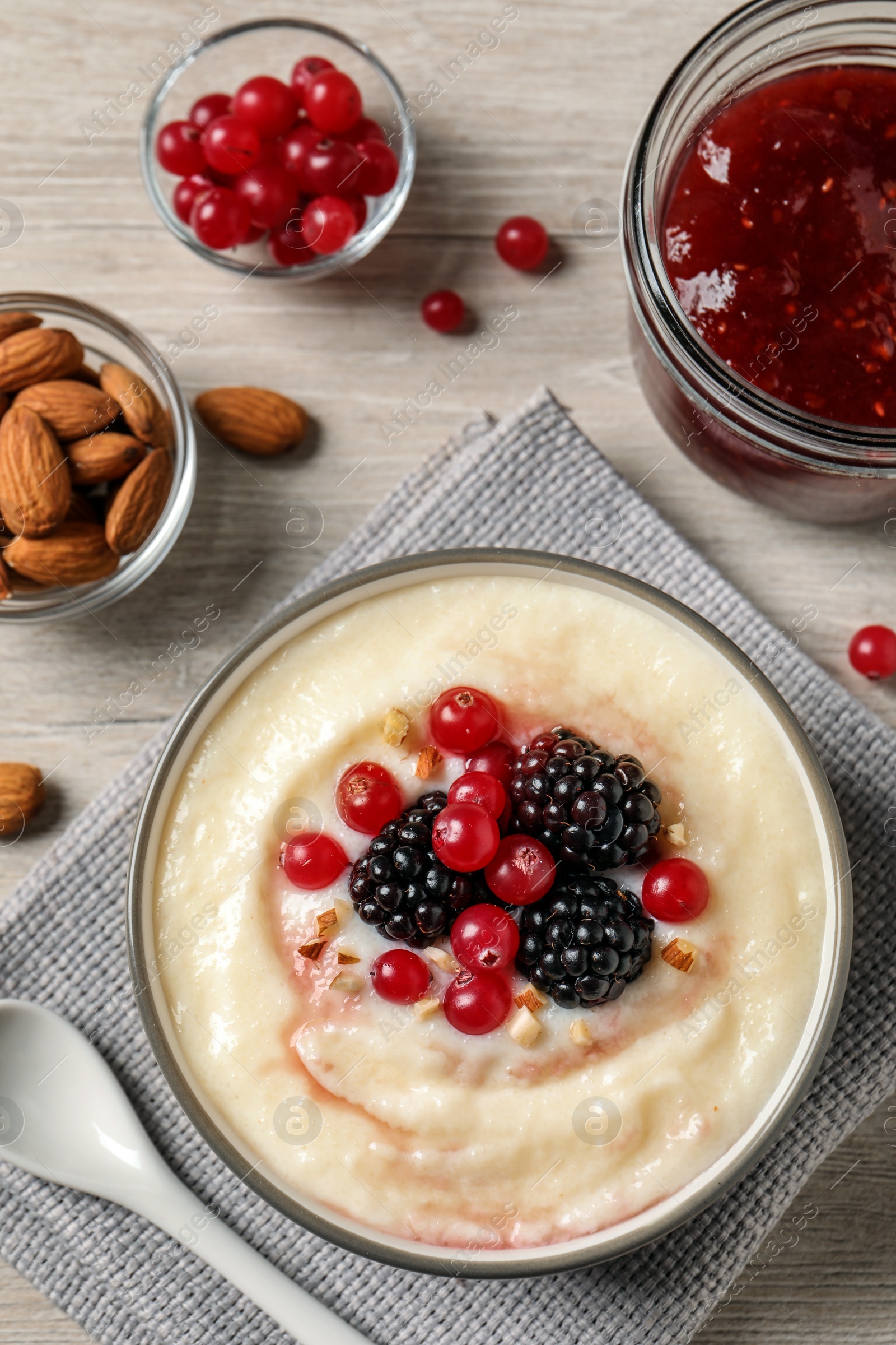 Photo of Delicious semolina pudding with berries on wooden table, flat lay