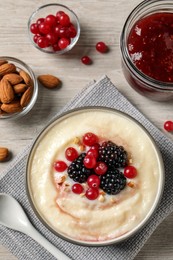 Photo of Delicious semolina pudding with berries on wooden table, flat lay