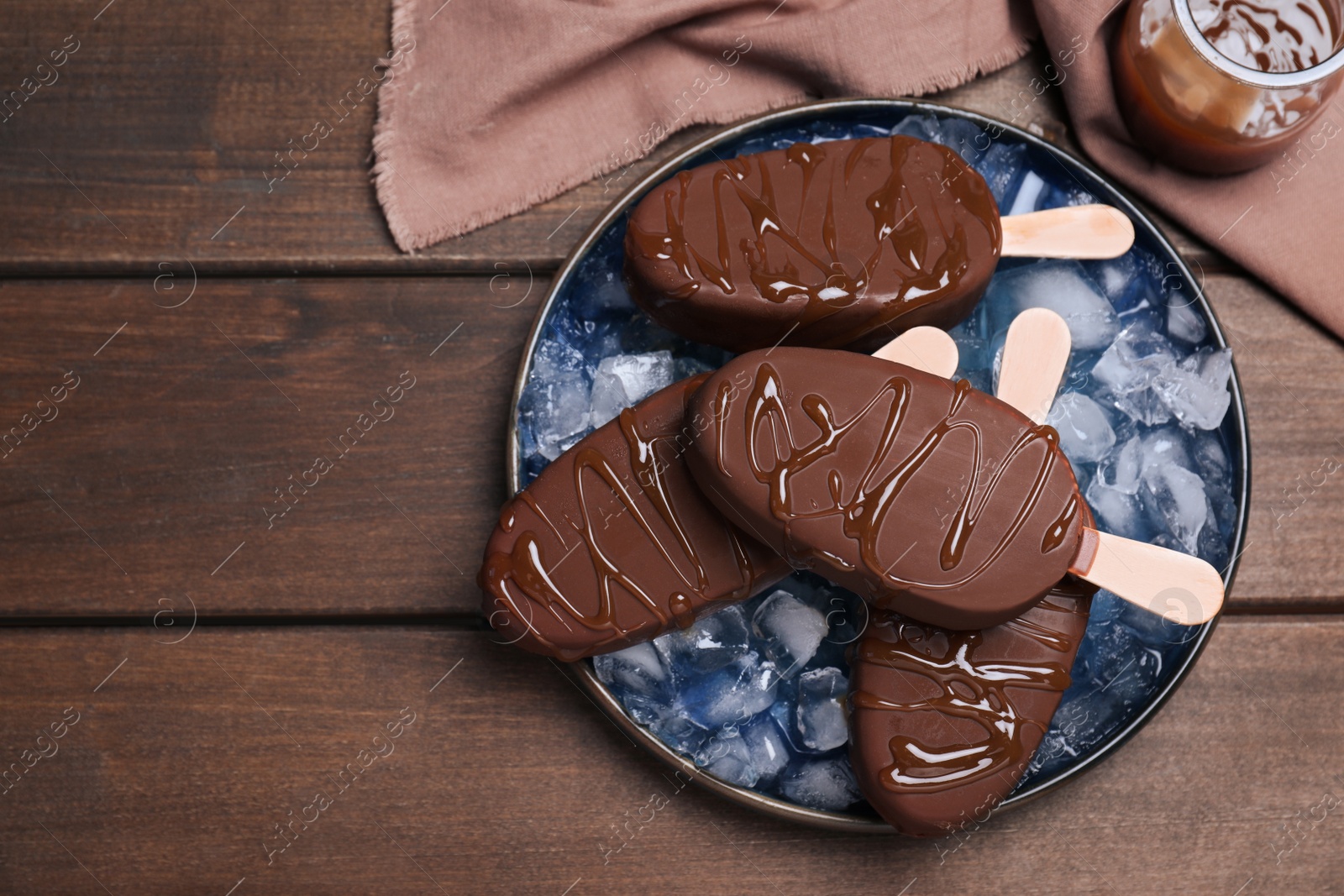 Photo of Delicious glazed ice cream bars and ice cubes on wooden table, flat lay. Space for text