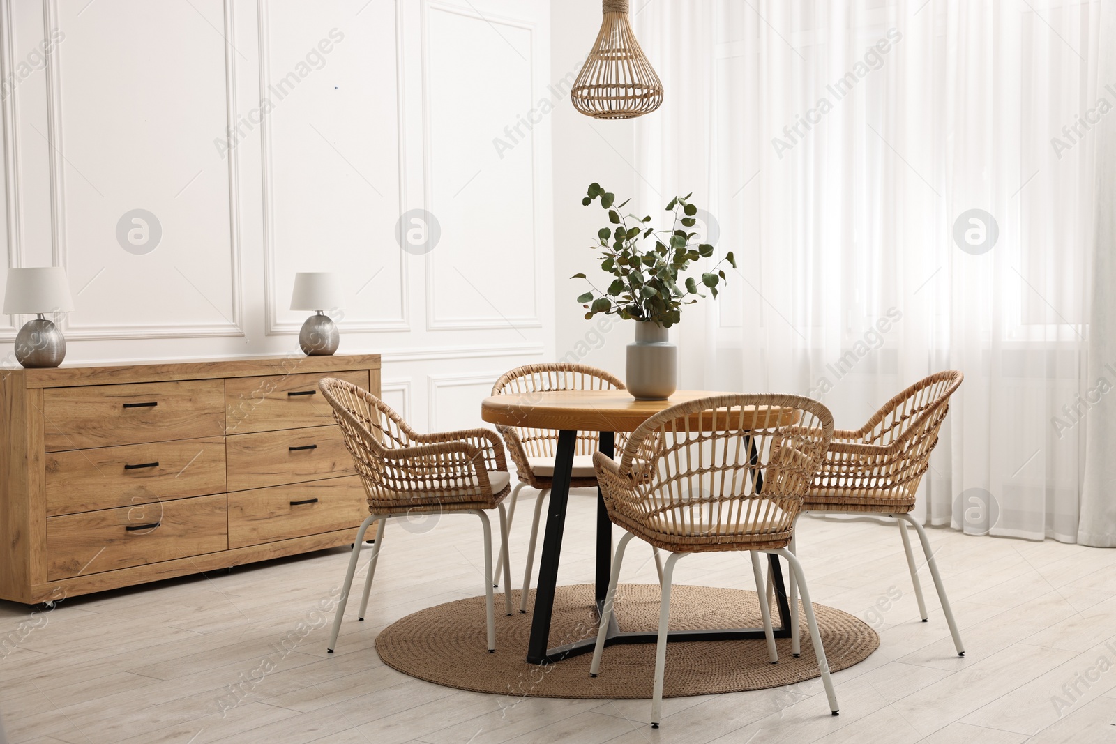 Photo of Dining room interior with comfortable furniture and eucalyptus branches