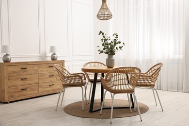 Photo of Dining room interior with comfortable furniture and eucalyptus branches