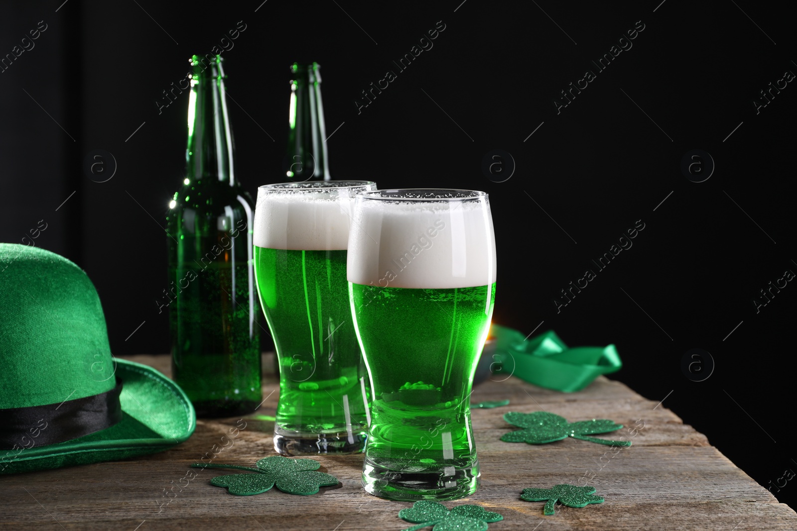 Photo of St. Patrick's day party. Green beer, decorative clover leaves and leprechaun hat on wooden table. Space for text
