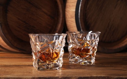 Photo of Glasses of whiskey on wooden table. Space for text